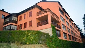 Um edifício de vários andares, com varandas, janelas amplas e base de pedra.