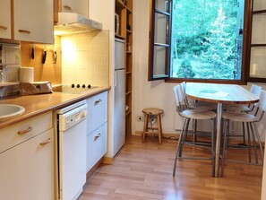 A modern kitchen with a wooden countertop, a built-in oven, and a window with a view of trees. - Studio 2 rooms Pool, Cadí Views, Gym and Games Area (Enveitg)