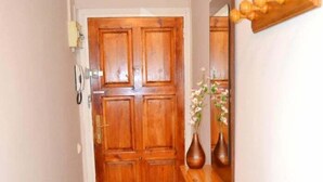 Une porte en bois, avec un miroir au-dessus, et un vase rempli de fleurs placé sur une table en bois, à côté de la porte.
