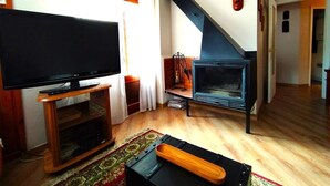 Un salon avec une télévision, une cheminée et un escalier.