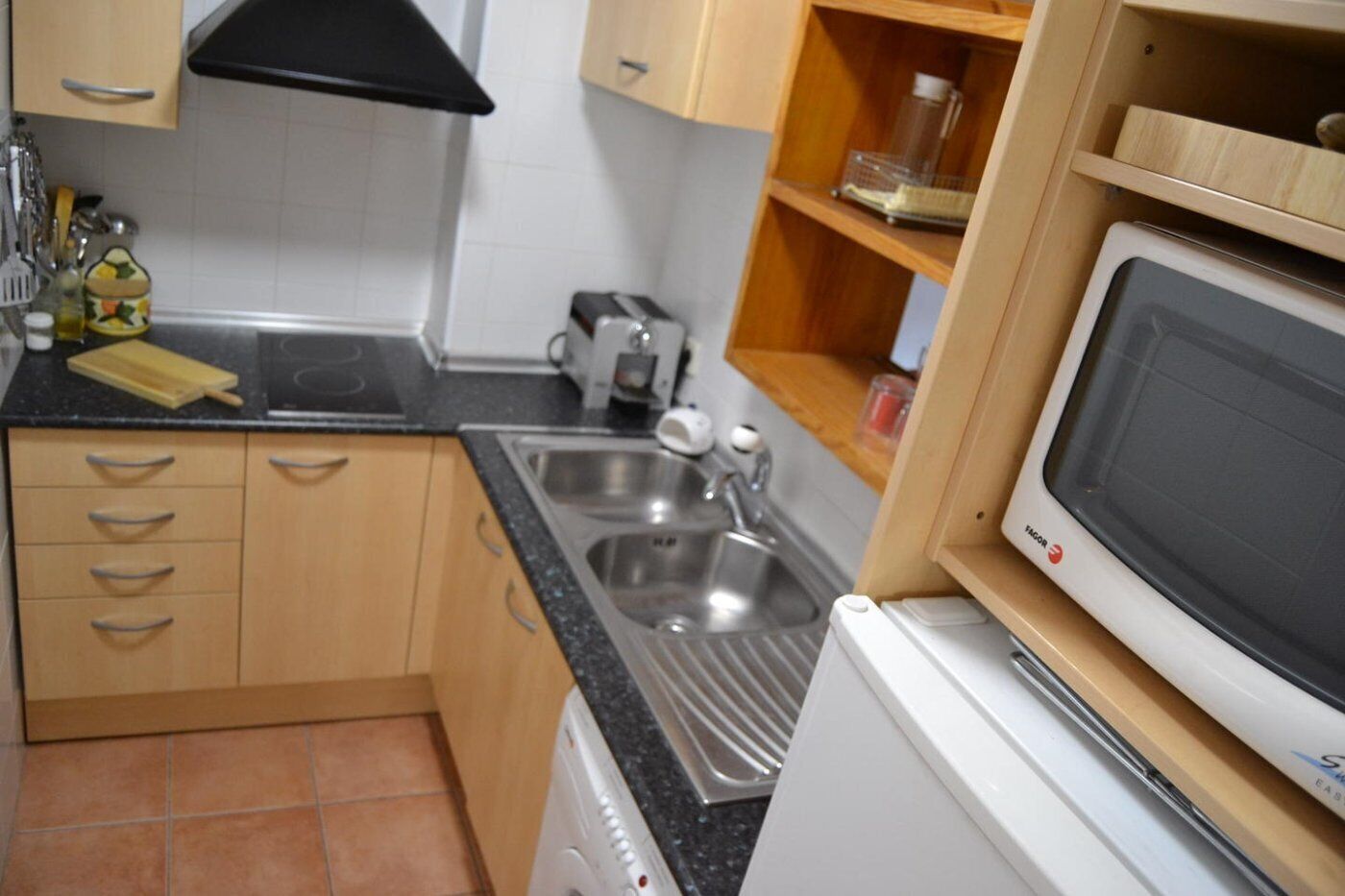 Een kleine keuken met een spoelbak, een broodrooster en een magnetron.