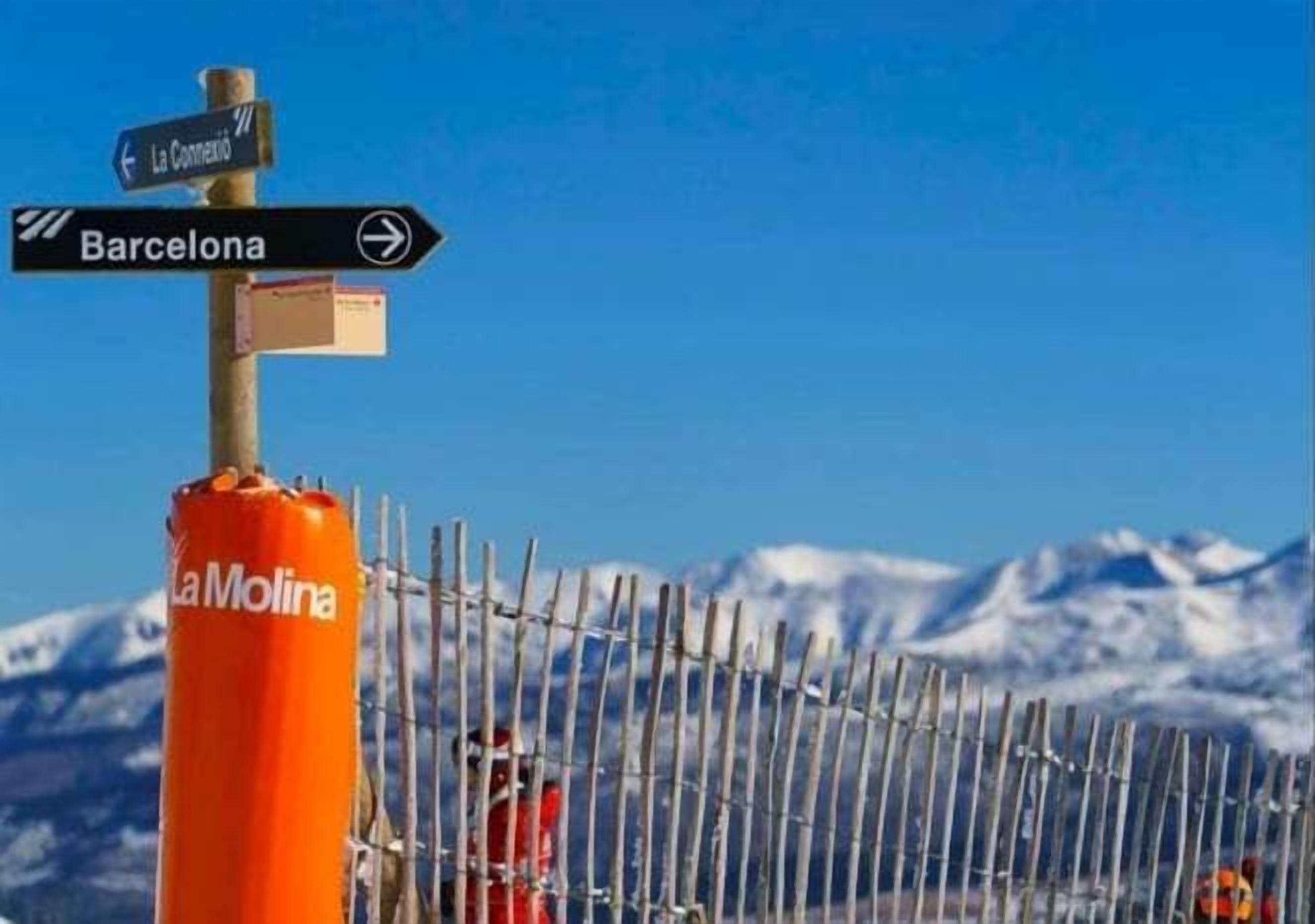 A directional signpost with arrows pointing towards La Concepción and Barcelona, and a La Molina branded orange cylinder.