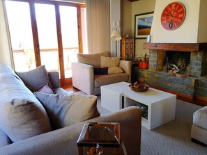 A cozy living room with a fireplace, a sofa, a coffee table, and a clock on the wall.