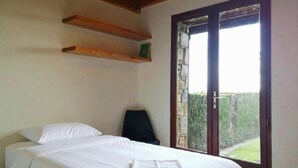 Une chambre à coucher avec un lit, une chaise et une fenêtre donnant sur un paysage verdoyant.