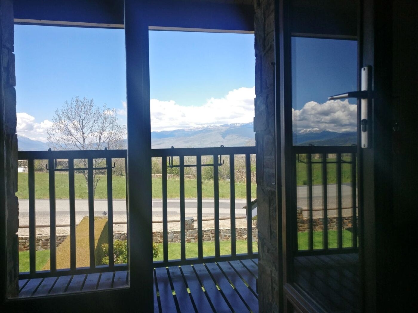 Un balcón de madera con vistas a una carretera y montañas.