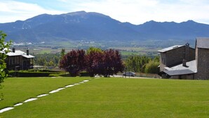 A grassy field with a stone building and a tree with red leaves. - Apartment 3 rooms Fireplace, Private Garden & Cadí Views (Ger)