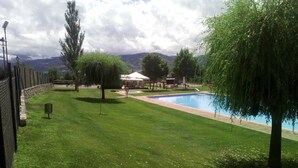 A well-maintained lawn with a swimming pool, a gazebo, and a view of distant mountains. - Apartment 3 rooms Fireplace, Private Garden & Cadí Views (Ger)