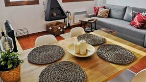 A cozy living room with a fireplace, a sofa, and a dining table with placemats. - Ground Floor 1 room Pool, Fireplace & Private Garden (Osséja)