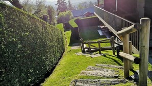 A wooden staircase leading to a building with a balcony, surrounded by a well-maintained hedge and a view of a distant town. - Ground Floor 1 room Pool, Fireplace & Private Garden (Osséja)