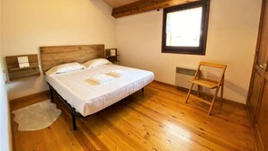 A bedroom with a wooden bed, a small chair, a window, and a radiator. - Duplex 2 rooms 6 Pax, Fireplace, Views, Dishwasher & Washer (Bourg-Madame)