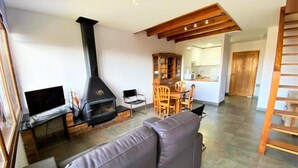 A living room with a fireplace, a sofa, a TV, and a dining area with chairs and a table. - Duplex 2 rooms 6 Pax, Fireplace, Views, Dishwasher & Washer (Bourg-Madame)
