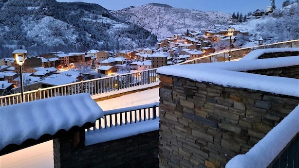 A snow-covered village with stone buildings and a stone bridge.