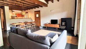 A modern living room with a grey sofa, wooden dining table, and a TV.