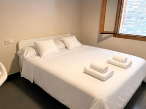 A neatly made bed with white linens and two rolled towels on the foot of the bed. - Townhouse 4 Bed Pellet Stove, Private Garden & Garage (Martinet)