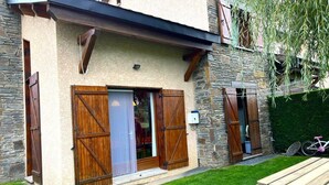 Ein zweistöckiges Haus mit Steinmauern, Holzläden und einer Veranda.