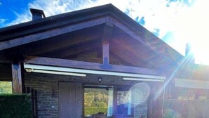 A rustic cabin with a stone exterior, a covered porch, and a view of the surrounding landscape.