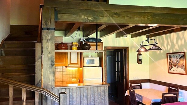 A kitchen with a wooden staircase, a dining area, and a view of the outside.