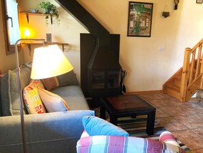 Una sala de estar con sofá, lámpara, chimenea y escalera.