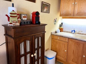 A kitchen with wooden cabinets, a countertop, a sink, and various appliances including a coffee maker and a toaster.