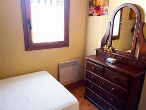 Een slaapkamer met een bed, een kaptafel met spiegel en een raam.