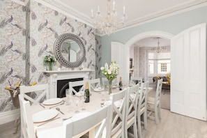 Ein Esszimmer mit Wand im Marmor-Muster, Kamin und einer Chandelier.