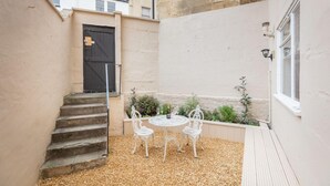 Une cour avec une table et des chaises, une porte et une fenêtre.