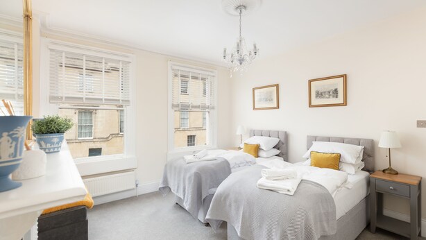 Une chambre d’hôtel avec deux lits, un bureau, une chaise, une petite table, une lampe et une plante en pot.