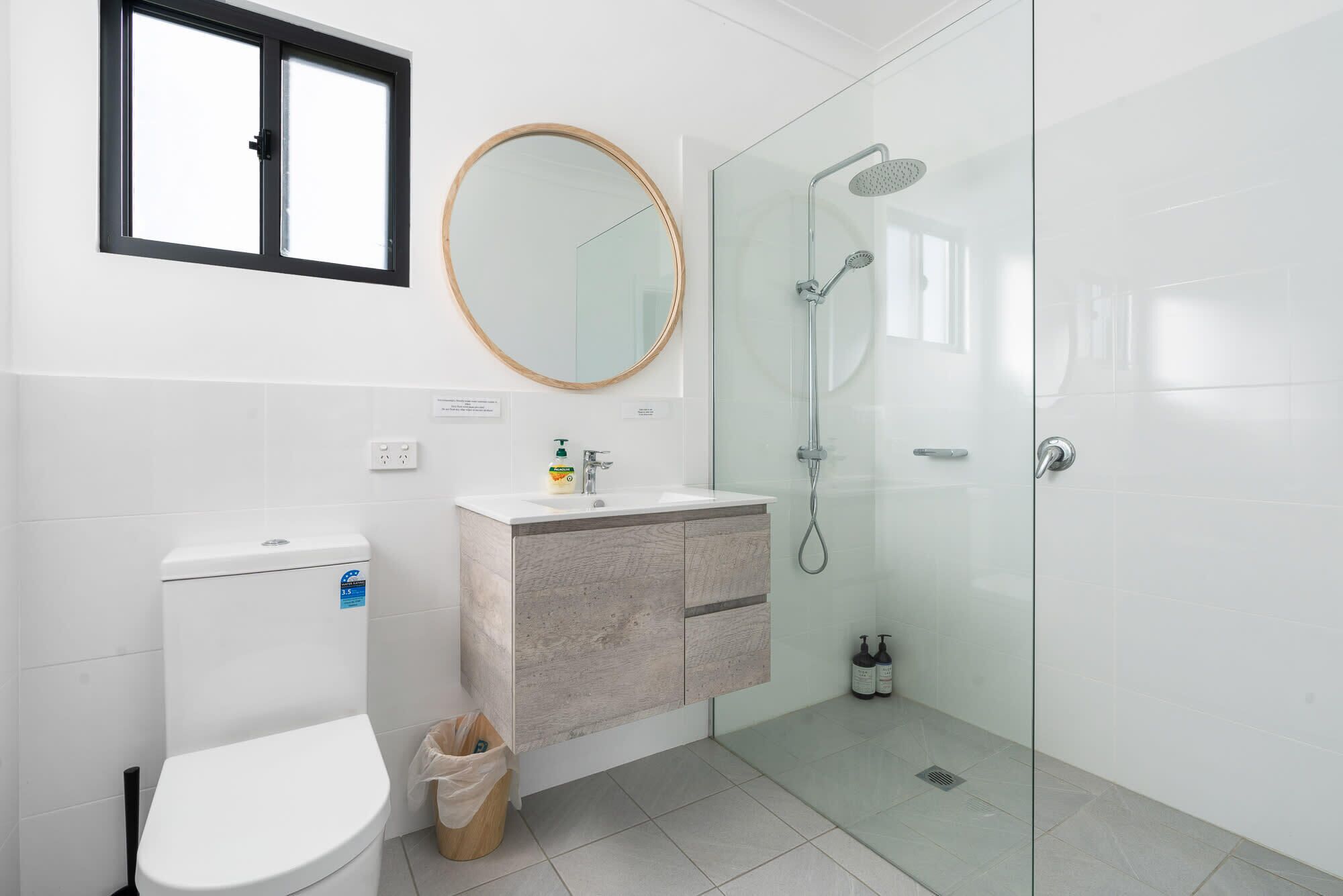 A modern bathroom with a toilet, sink, mirror, and glass-enclosed shower.