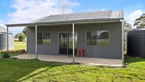 Un petit bâtiment d’un seul étage, doté d’une façade métallique, de grandes fenêtres et d’un patio couvert.