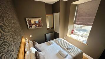 Een slaapkamer met een groot bed, een raam met uitzicht, een radiator en een spiegel aan de muur.