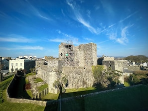 A historic stone castle with a central tower, surrounded by a moat and modern buildings in the background. - Halvard Apartments at Castletown (Castletown)