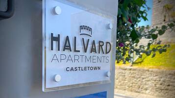 A sign for Halvard Apartments in Castle Town, featuring a website link and a catering service.