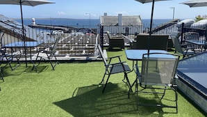 Une terrasse sur le toit avec des sièges extérieurs, une vue sur la mer et un phare en arrière-plan.