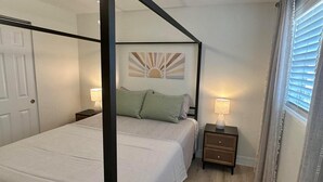 A four-poster bed with a white bedspread, two green pillows, and two nightstands with lamps. - The Turtle Nest 8 in Fort Myers Beach (Fort Myers Beach)