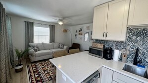 A compact kitchen with a central island, a dining area with a sofa, and a living area with a couch. - The Turtle Nest 8 in Fort Myers Beach (Fort Myers Beach)