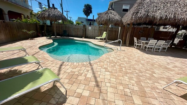 A swimming pool with a brick patio, surrounded by lounge chairs and thatched umbrellas. - The Turtle Nest 8 in Fort Myers Beach (Fort Myers Beach)
