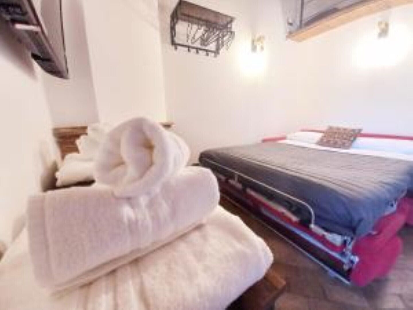 Een hotelkamer met een bed, een nachtkastje en een wandplank.
