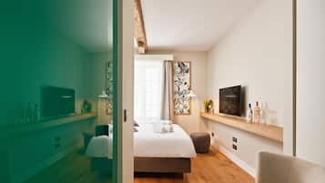 Una habitación de hotel moderna con cama, televisor, zona de estar y piso de madera.