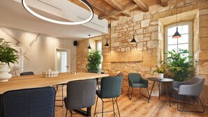 A modern interior with exposed wooden beams, a stone wall, and a wooden dining table with chairs. - Hotel Le Chevalier Bleu (Monpazier)