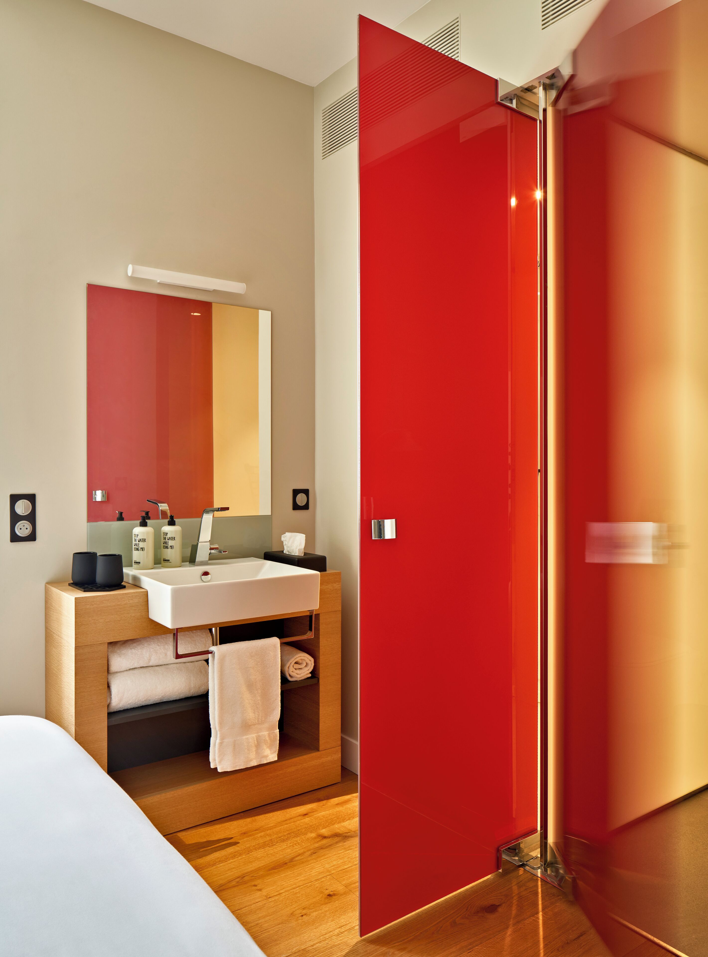 Un baño moderno con tocador de madera, un lavabo blanco y un espejo grande.