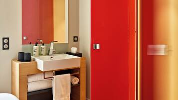 Un baño moderno con tocador de madera, un lavabo blanco y un espejo grande.