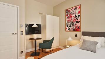 Una habitación de hotel con una cama, un escritorio con silla, un televisor y un cuadro en la pared.