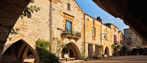 A stone building with arched doorways and a bench in the courtyard.