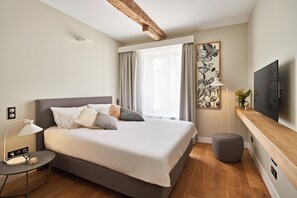 Relax in a serene space with a large bed, round ottoman, and flat-screen TV.