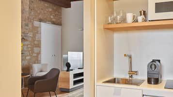 Una cocina moderna con armarios blancos, techo de madera y pared de piedra.