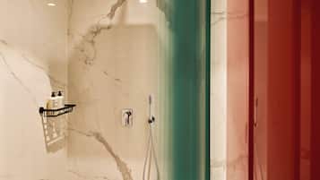 Un baño con pared de mármol, ducha con cabezal de ducha manual y cortina verde.