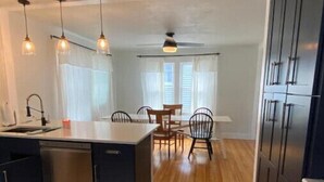 A kitchen with wooden flooring, a dining area with a table and chairs, and built-in cabinets. - Ocean View cottage in Indian Neck. Super Host with 5-Star Rating (Branford)