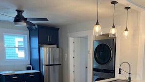 A modern kitchen with a central island, bar stools, stainless steel appliances, and pendant lighting. - Ocean View cottage in Indian Neck. Super Host with 5-Star Rating (Branford)