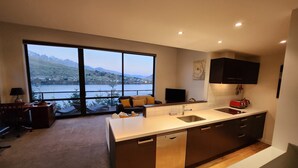 Une cuisine moderne dotée d’un grand îlot central, d’un lave-vaisselle intégré et offrant une vue sur un lac et des montagnes.