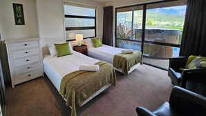 Une chambre d’hôtel avec deux lits, une commode, une table de chevet avec une lampe et une vue sur l’extérieur.